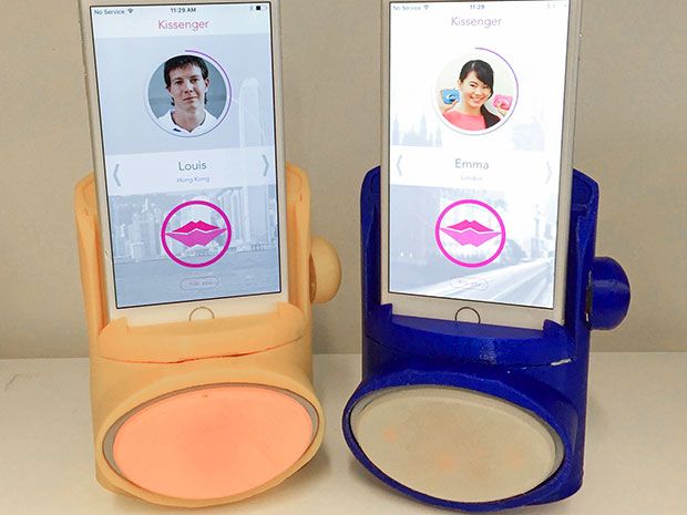 Two iPhones are connected to Kissenger devices. The phone screen shows the Kissenger app that enables kiss transmission during a video call. 