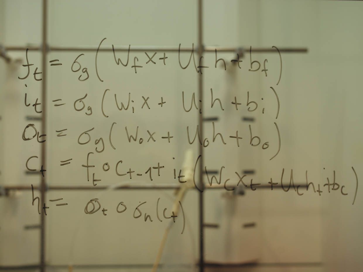 A photo shows equations drawn on a transparent blackboard.