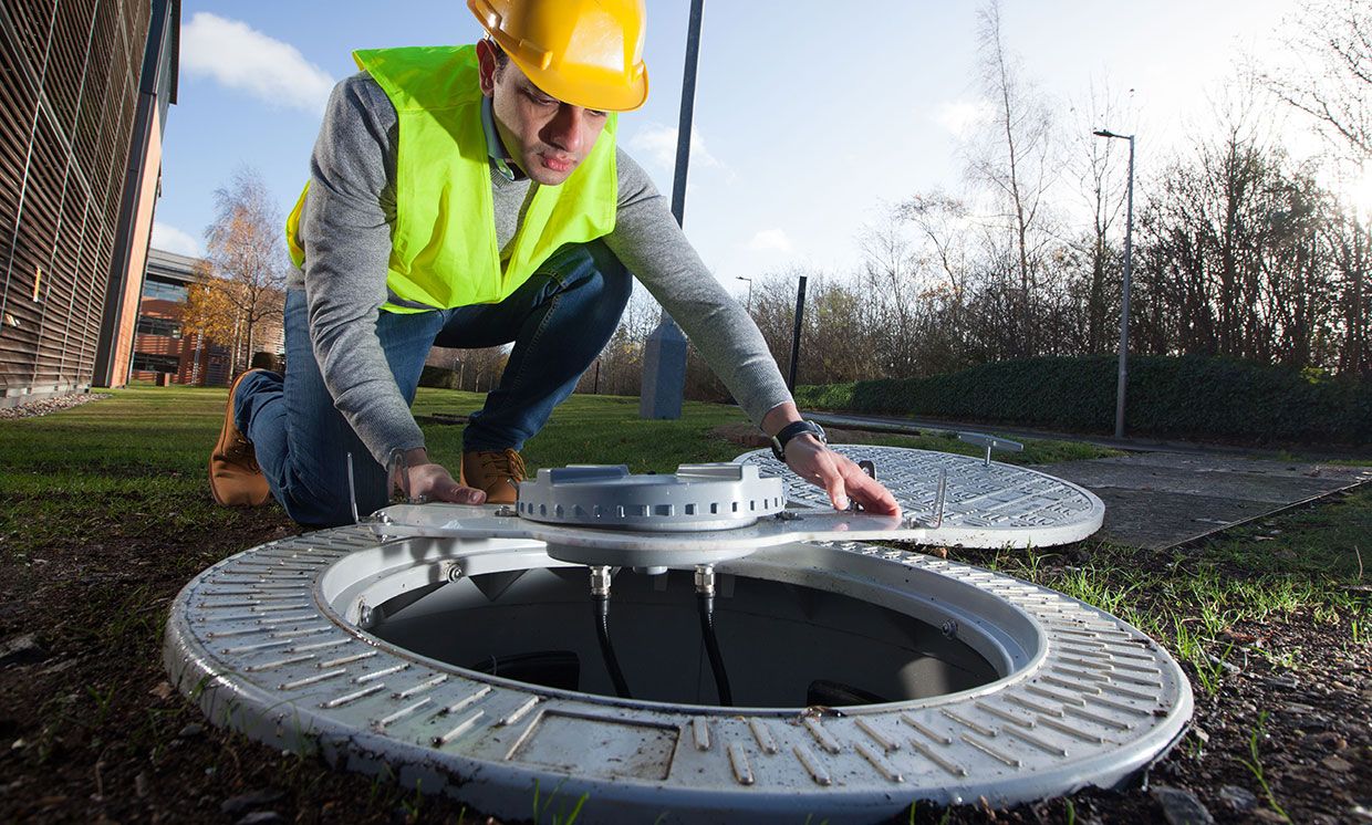 Employee installing a 4G-enabled manhole cover.