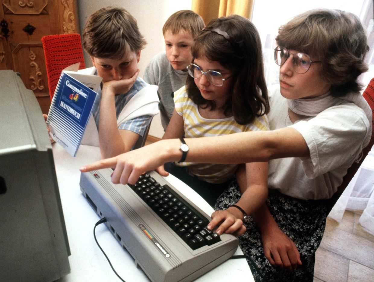 Photo of four children looking at a Commodore computer screen.