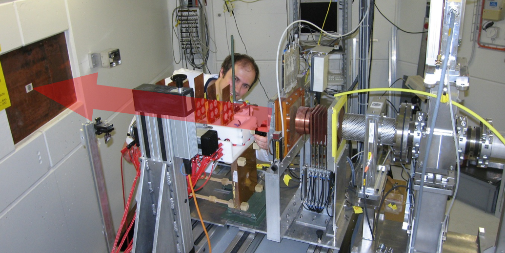 Test setup in a proton beam at Paul Scherrer Institute in Switzerland. The direction of the beam is indicated by a red arrow.