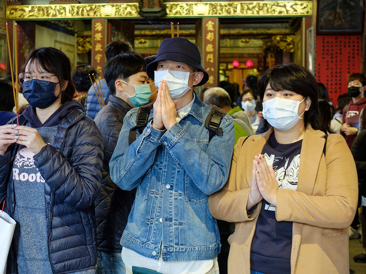 Photo du 23 février 2020 à Taipei, Taiwan montre des gens portant des masques chirurgicaux dans un temple.
