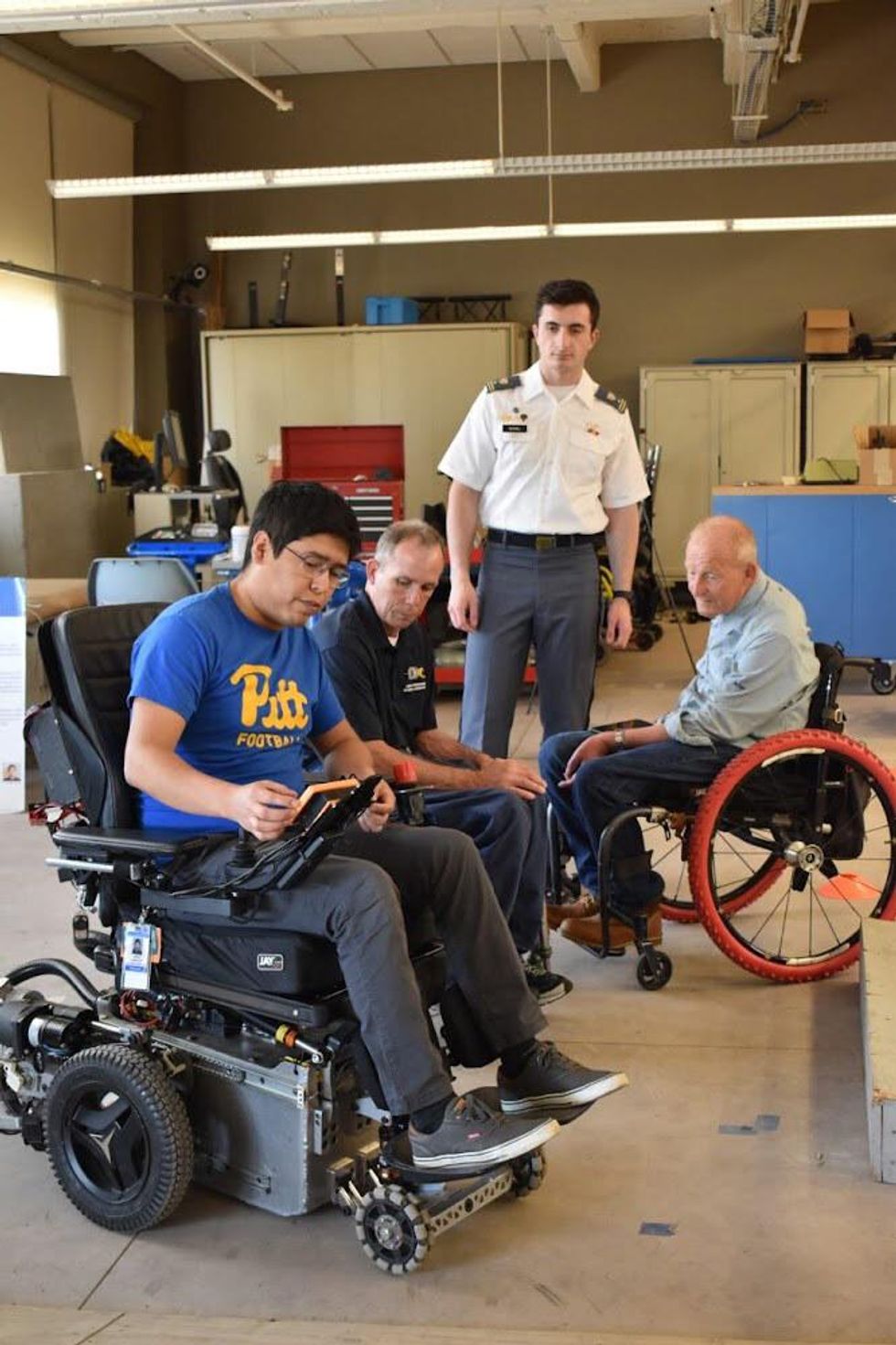 3 people sitting in a wheelchair and 1 man standing