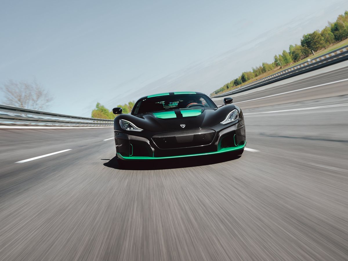 A black and green car moves at high speed down a road, shown with extreme motion blur.