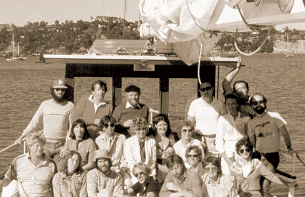 A black and white photo of a group of 20 people posing on the deck of a large sailboat.