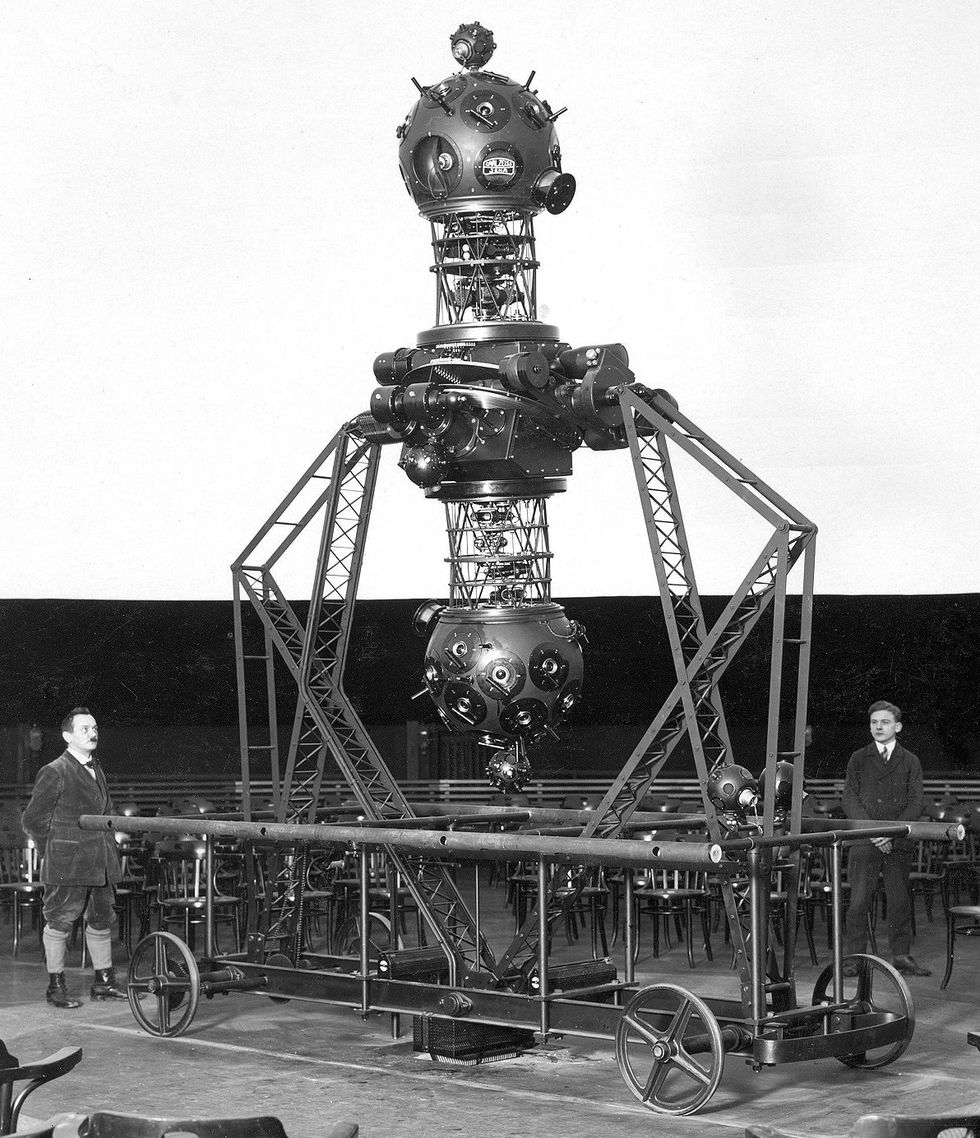 A black and white photo of a large complex dumbbell-shaped apparatus mounted on a wheeled cart.