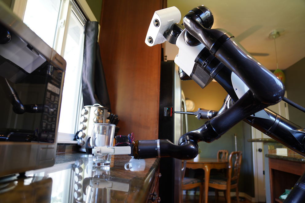یک ربات دو مسلح سیاه و سفید لیوانی را در آشپزخانه می‌گیرد