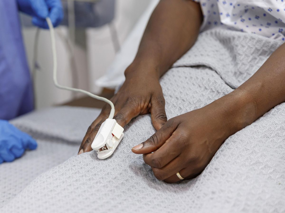 A Black hospital patient with a pulse oximeter on their finger