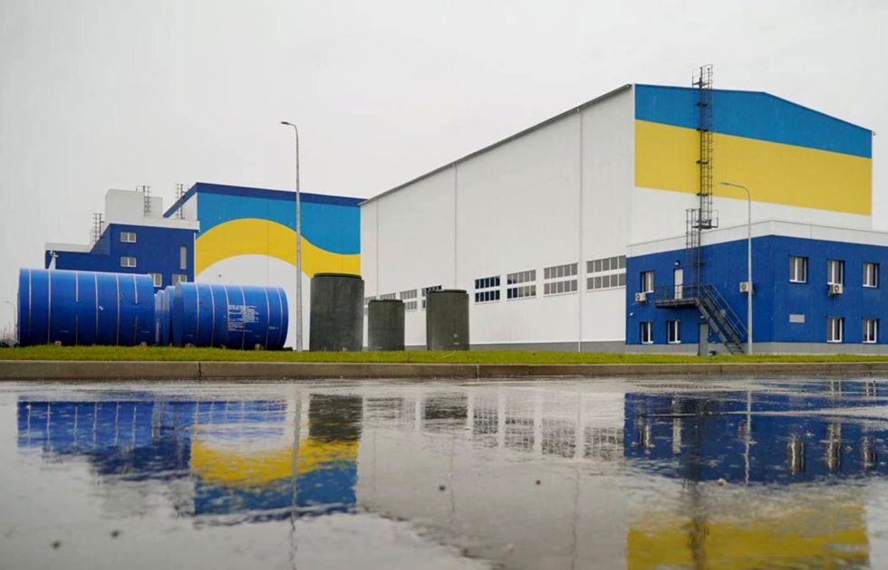 A building with blue drum containers to the left.