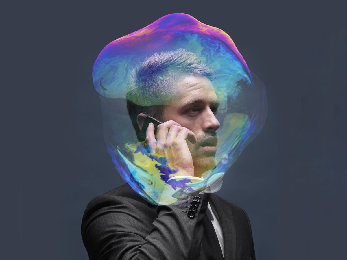 A businessman talks on his cell phone. His head is encompassed by a colorful transparent bubble.