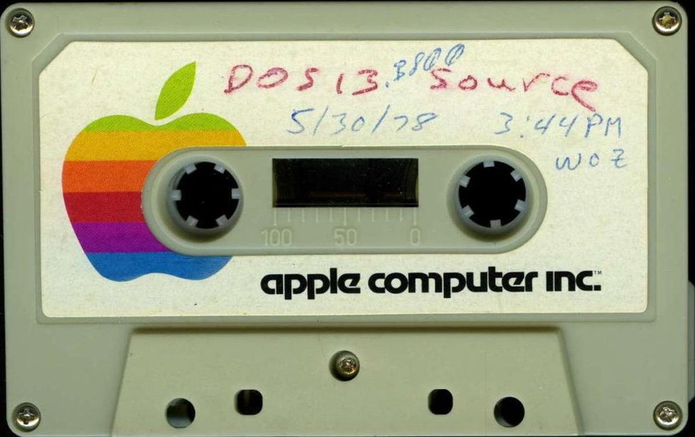 A cassette tape with a label that says "apple computer inc." with handwritten "DOS 13 source" and "5/30/78 3:44pm Woz". 