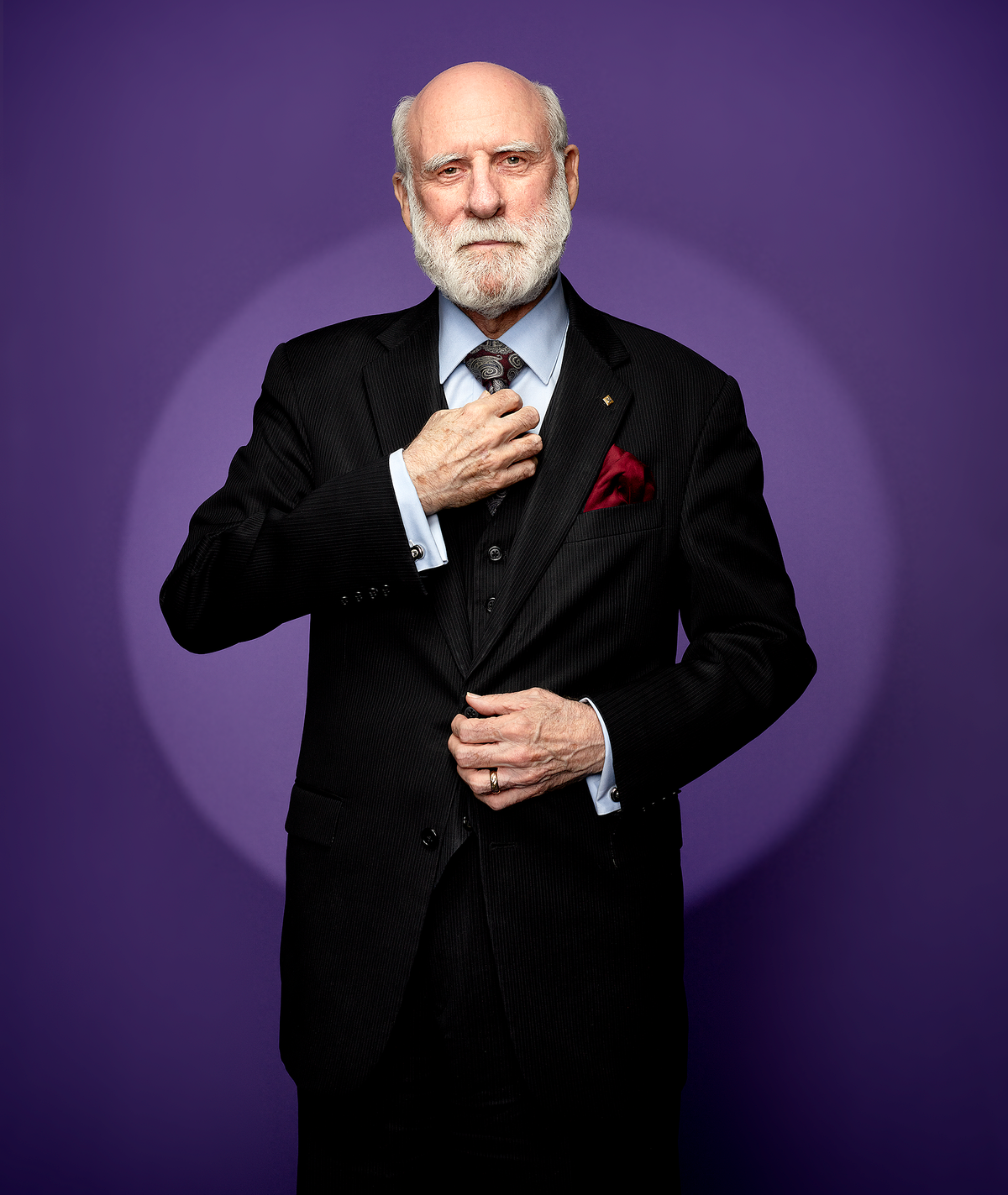 A color photo of a man with a beard in an elegant three-piece suit.