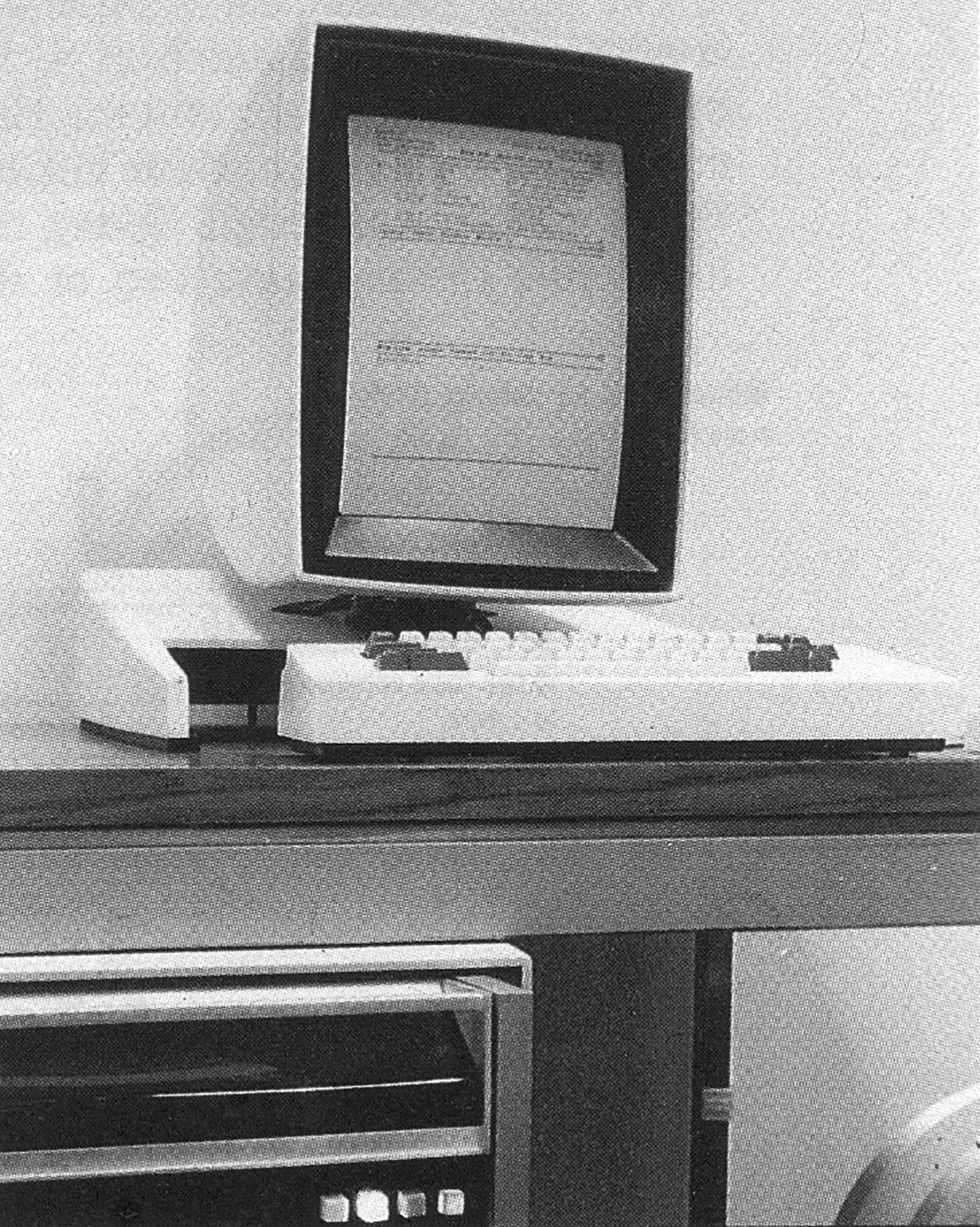 A computer monitor with a chunky white keyboard sitting on a desk