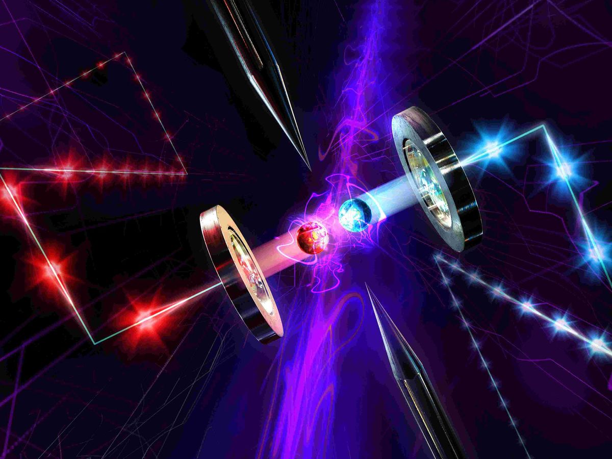 A conceptual illustration shows two colliding glowing balls held in beams of color in front of two metallic toroids.