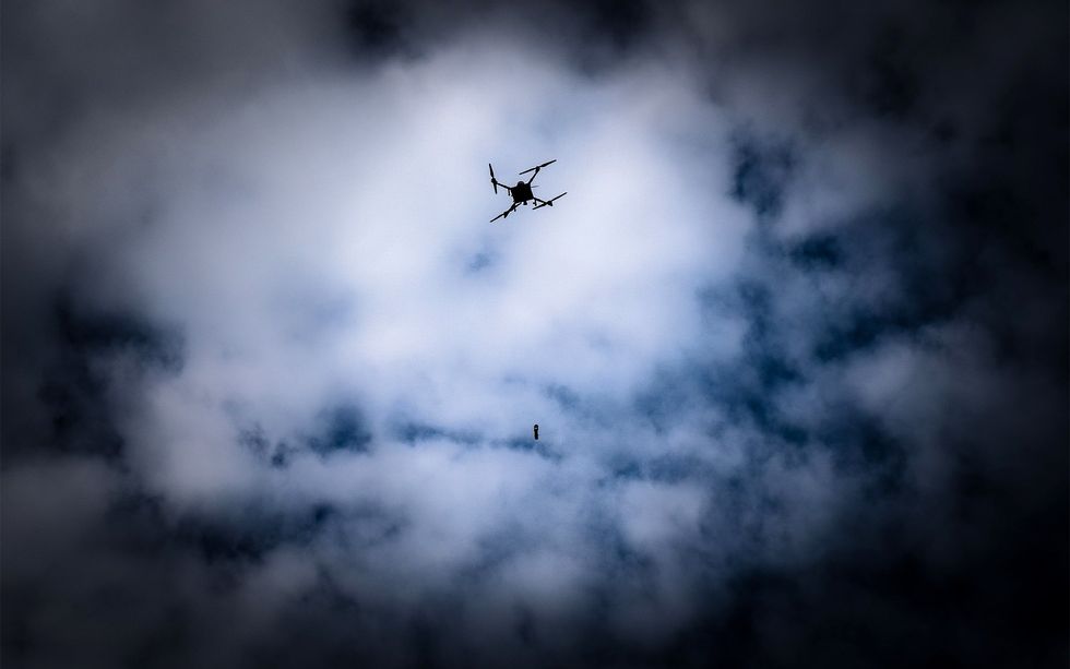 A dark, cloudy sky behind the silhouette of a drone and an anti-tank grenade