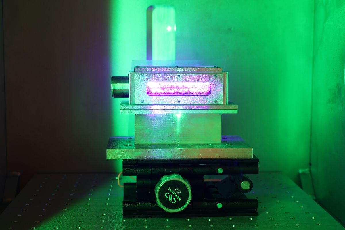 A device sits in a chamber bathed in green light.