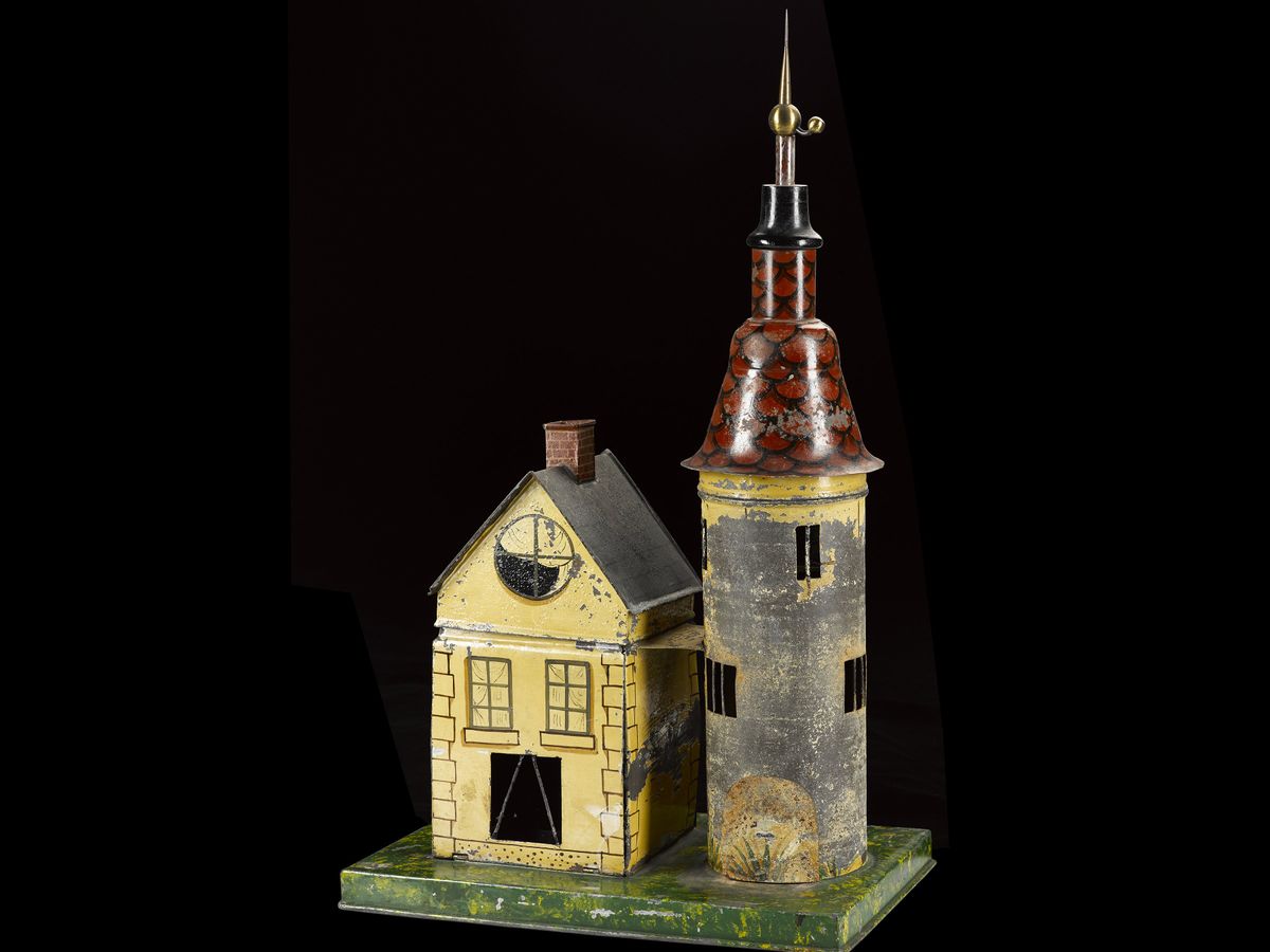  A dollhouse-size model house and tower made of painted metal. The tower has a long rod protruding from its top.