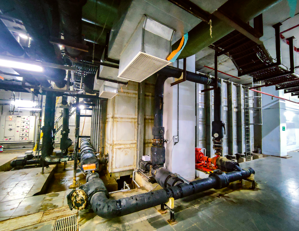 A floor-to-ceiling concrete structure surrounded by thick black pipes. 