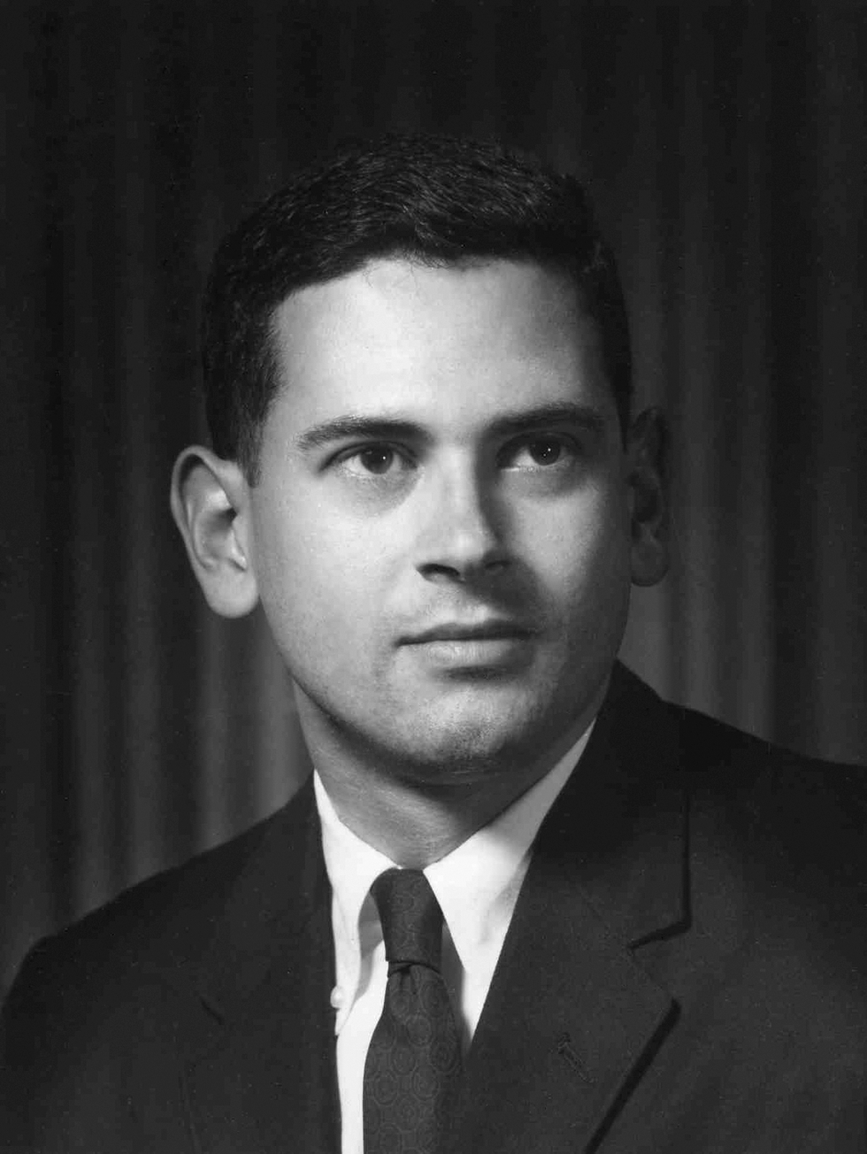 A formal black and white portrait of a man wearing a suit and tie.