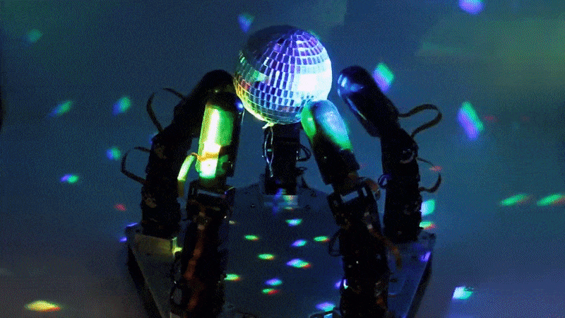 A GIF showing five robotic fingers rotating a glittering disco ball casting rainbows around the room