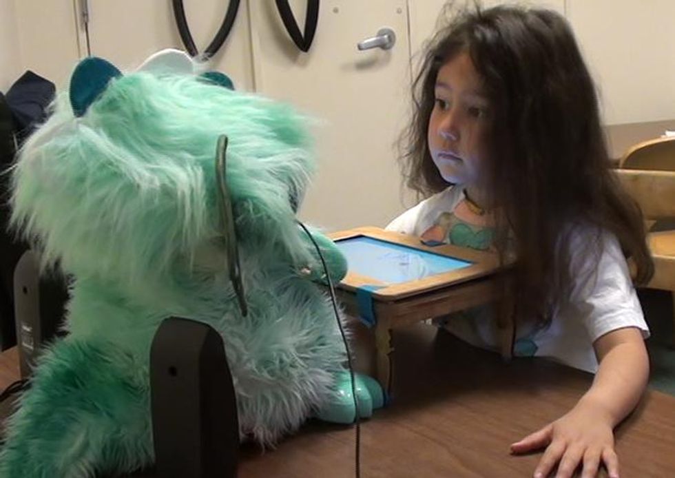 A girl looks up at DragonBot during a storytelling game.