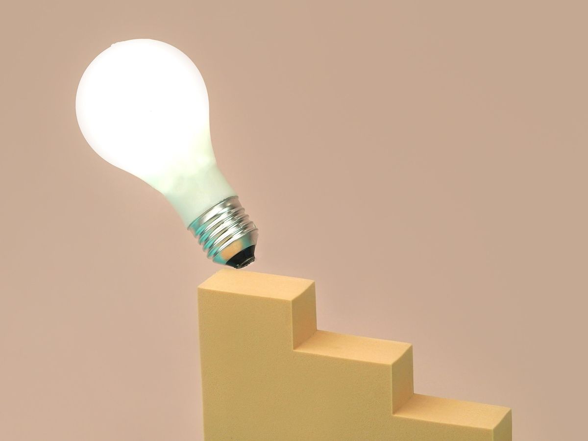 A glowing lightbulb tips off the end of a stepped block.