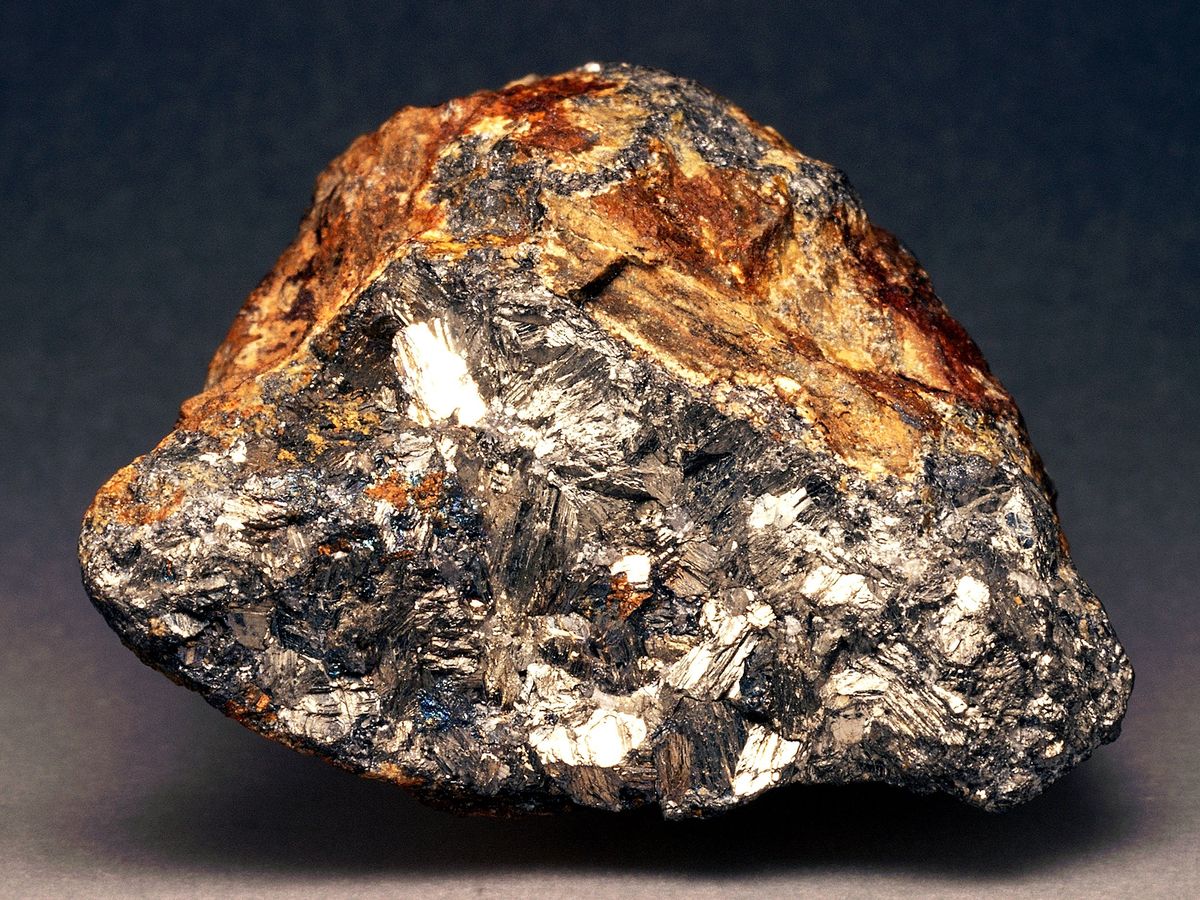 a gold and gray rock sitting on a dark gray background