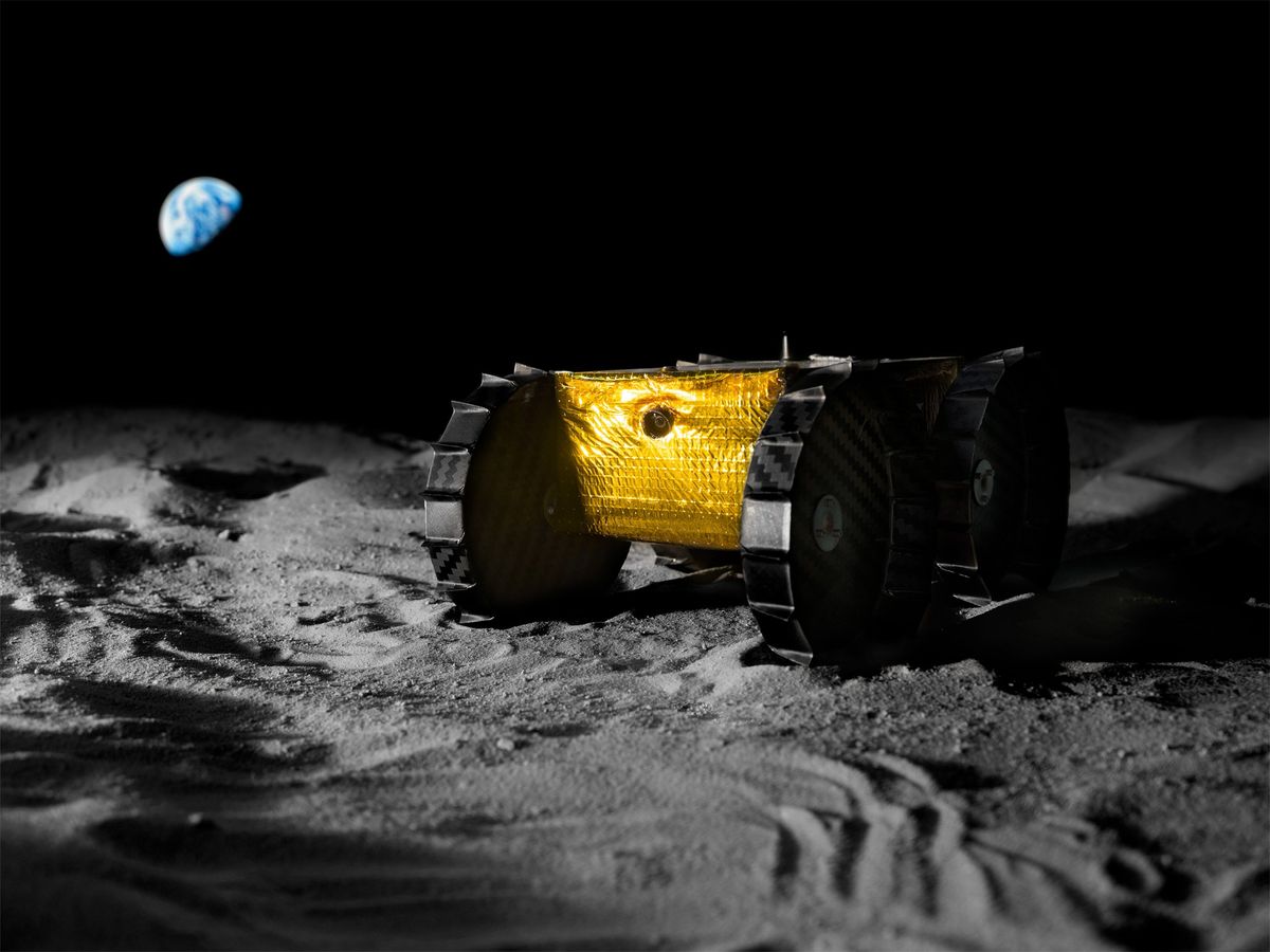 A golden box with four wheels is motionless on a gray powdery surface with a black sky and the Earth in the background.