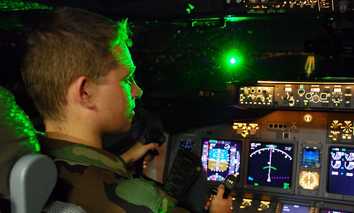 Air Force 2nd Lt. Paul LaTour is illuminated by a brilliant flash of green laser light during a simulated landing in a Boeing 737 flight simulator at the FAA's Mike Monroney Aeronautical Center in Oklahoma City, Okla.