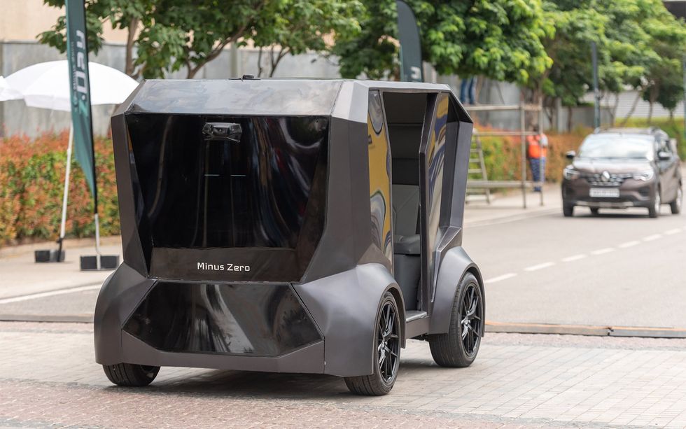 A grey self-driving vehicle labelled Minus Zero on a street