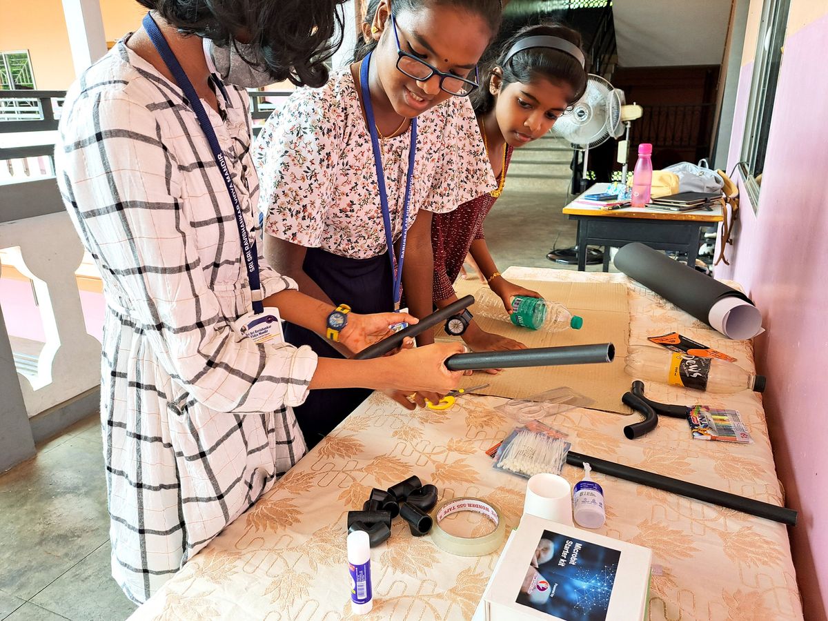 a group of young girls working on a project together involving black rods 