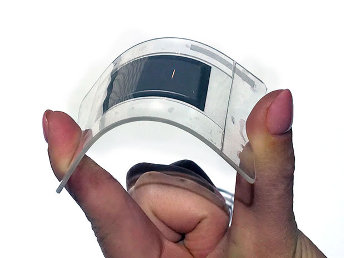 A hand flexing between its fingers a clear plastic sheet with a dark rectangle in the center