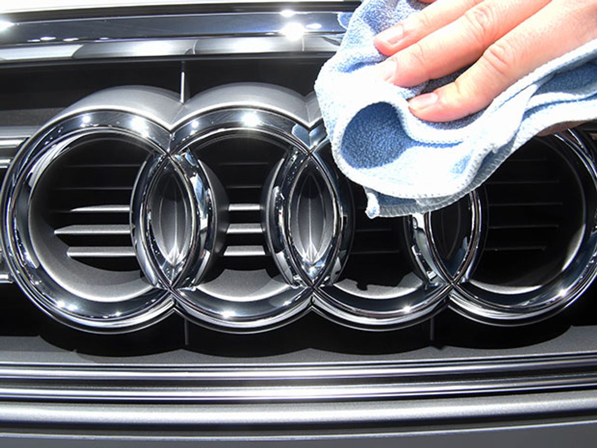 A hand polishing the Audi symbol, four interlocking rings.