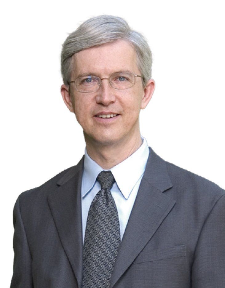 A headshot of a silver-haired man in a suit and glasses.
