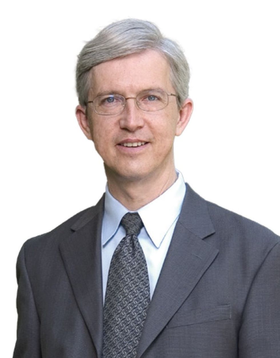 A headshot of a silver-haired man in a suit and glasses.