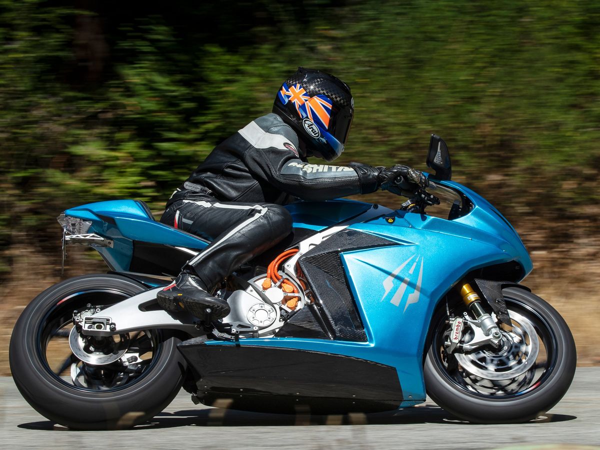 A helmeted person rides a blue motorcycle.