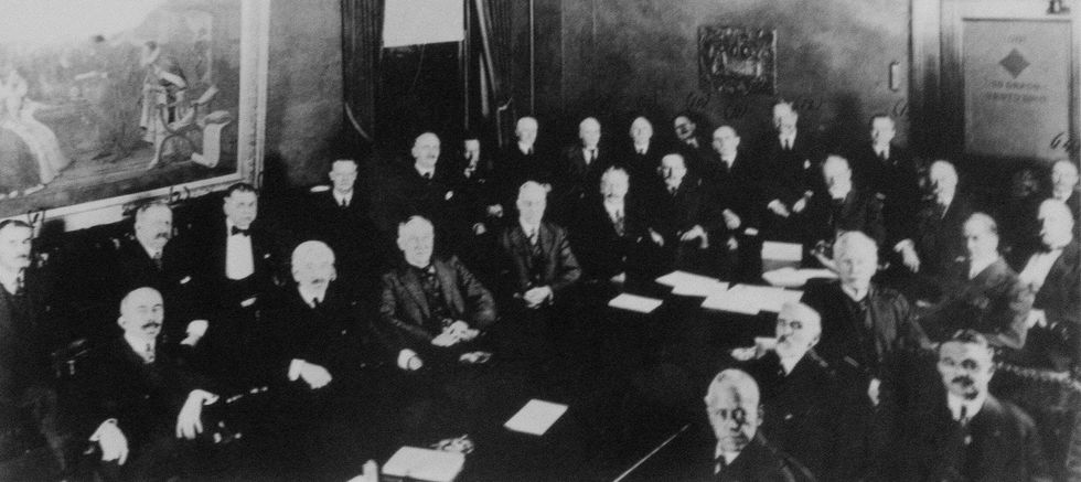 A historical image shows a group of men seated in rows around a stately table.
