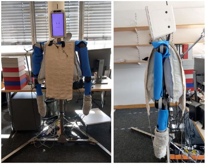 A humanoid robot torso with exposed robotic arms, a monitor for a head with a smiling face on it, with inflated chambers and heating pads on the torso.
