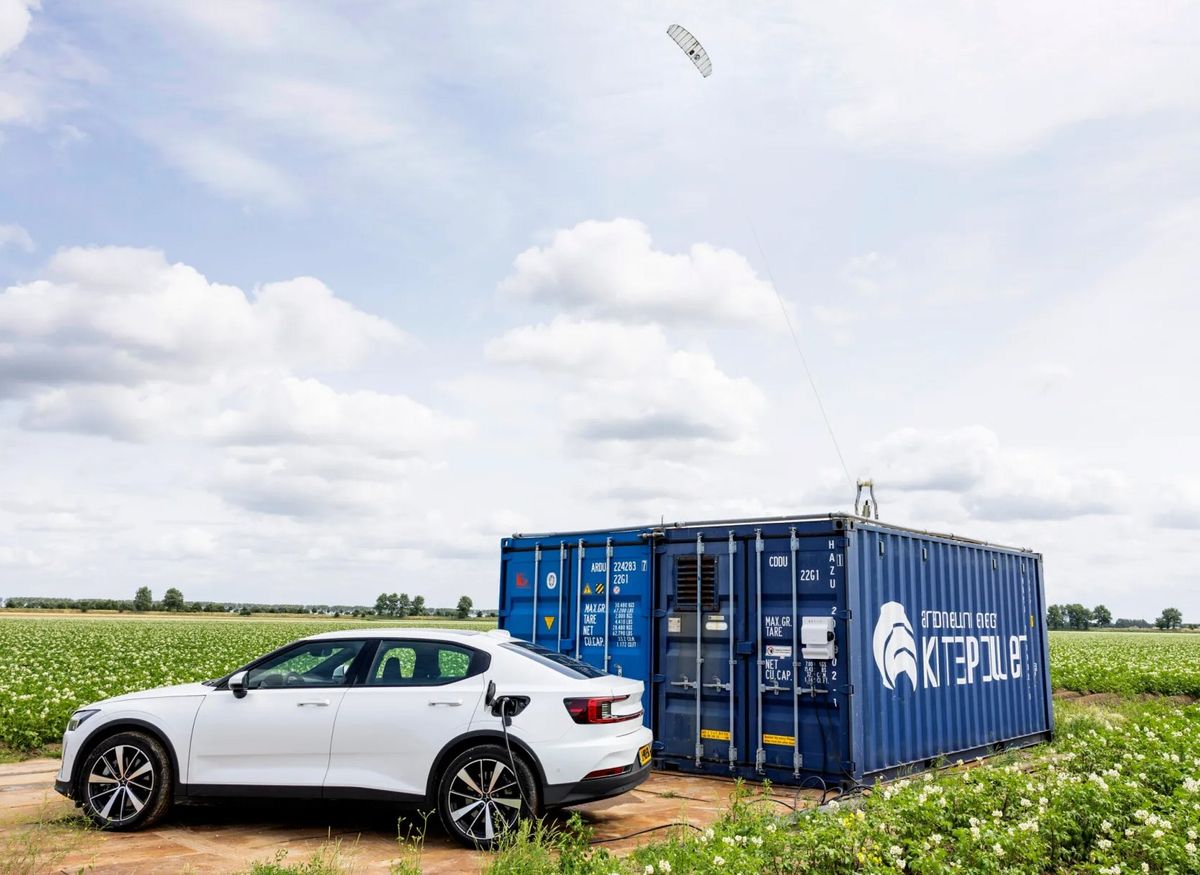 A large blue shipping container with a string attached to a floating device, and a car being charged from the container