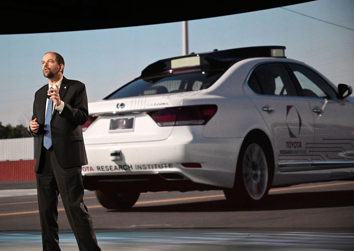 A man giving a presentation in front of a projection of a car.