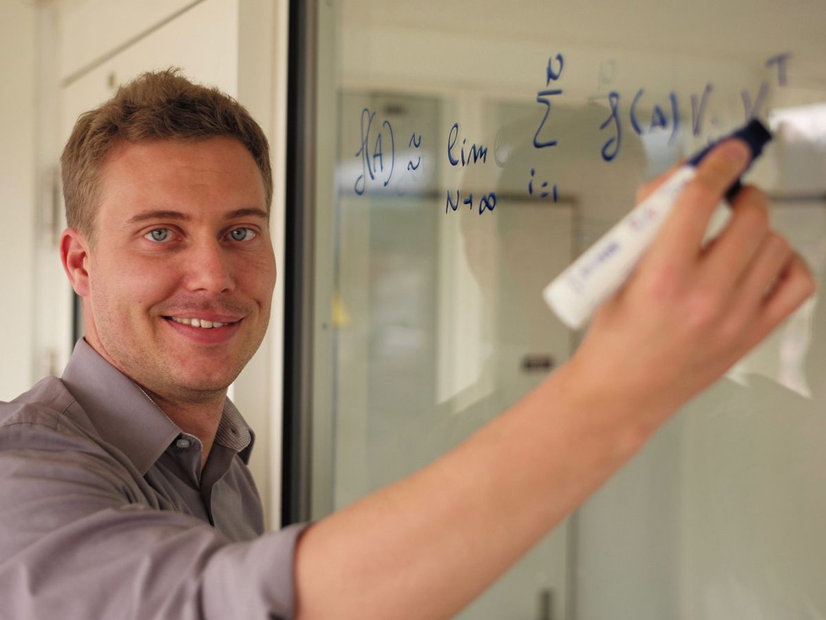 A man holding a marker in front of mathmatics.
