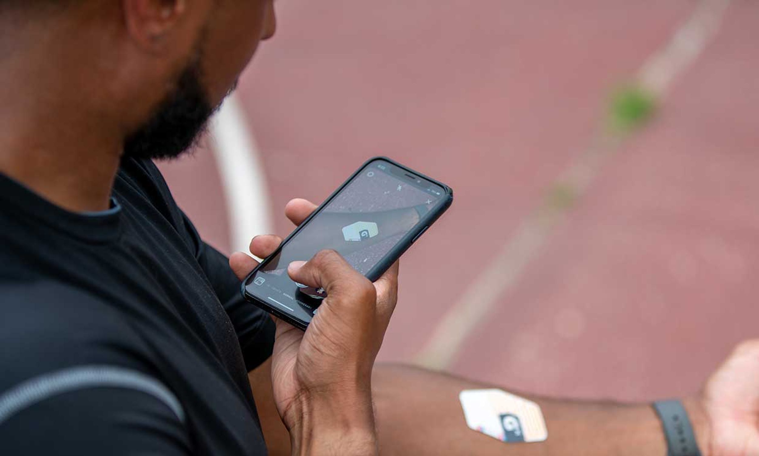 A man holding a smartphone scans his Gx Sweat Patch.