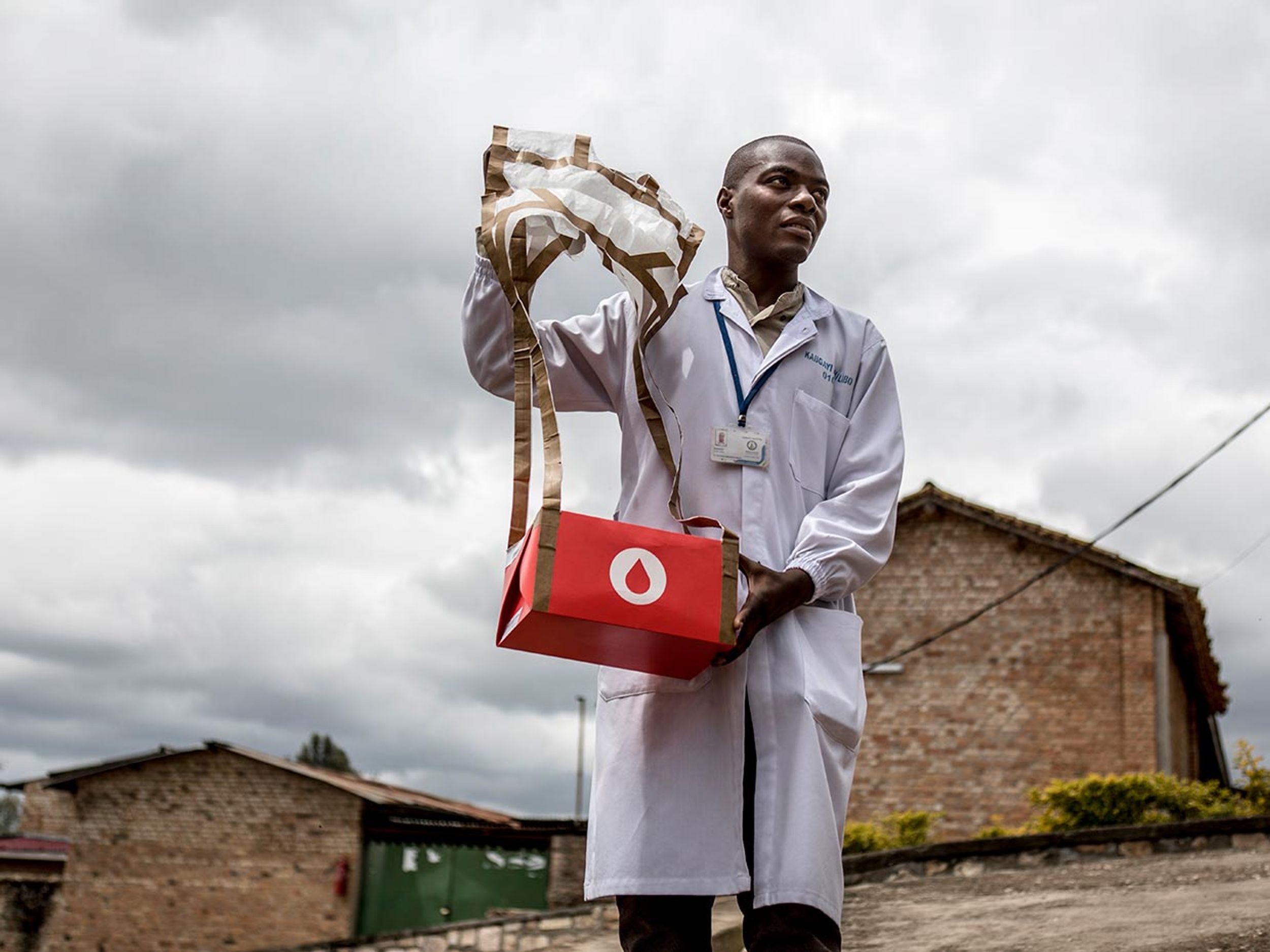 A man holding blood drone delivery at medical facility in Rwanda.