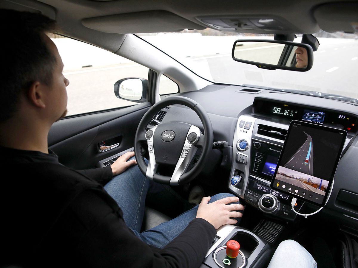 A man sits in the driver's seat of a Yandex driverless car equipped with manual controls and sensors such as lidar, cameras, and radars, as it undergoes testing on roads of Moscow; in November 2018.