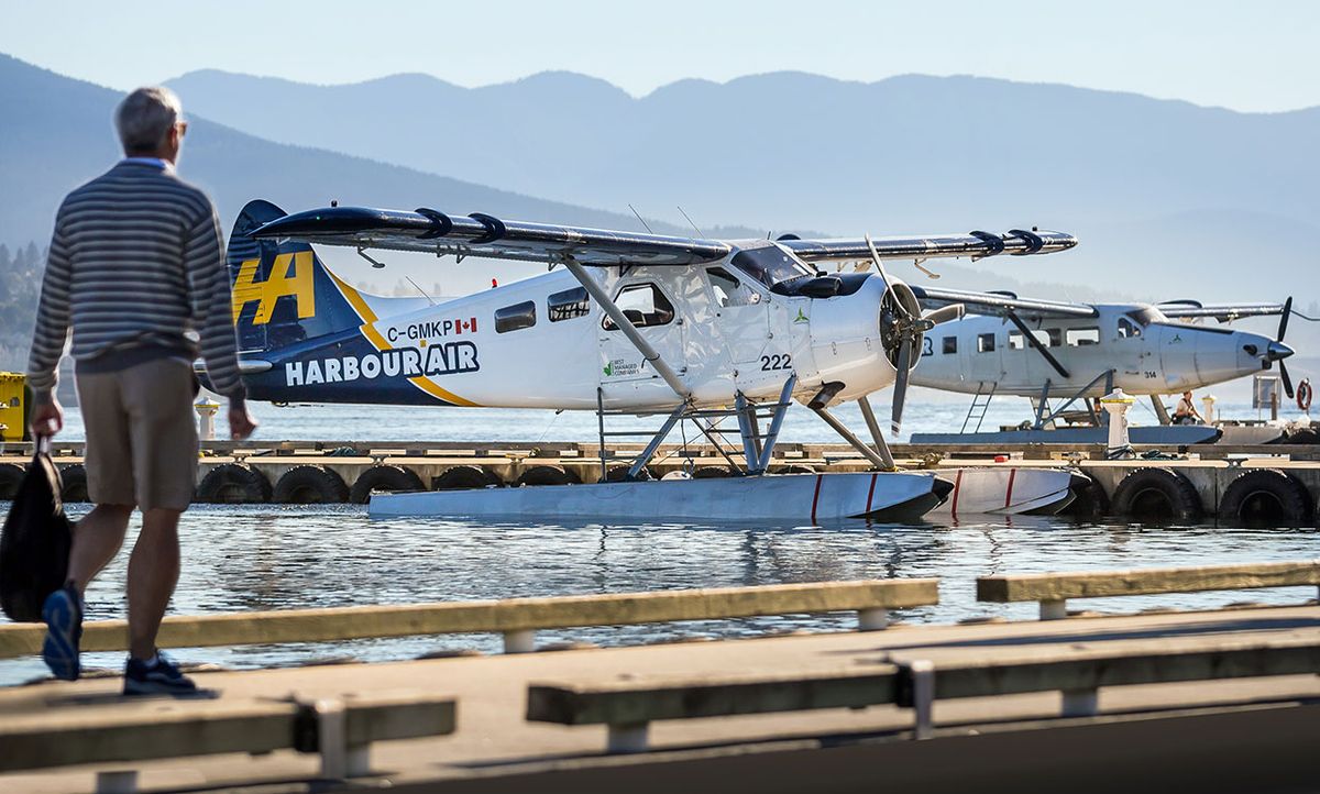 A man walks towards a Harbour Air Seaplane six-passenger Havilland Beaver aircraft, which will soon be retrofitted with a battery-powered electric motor.