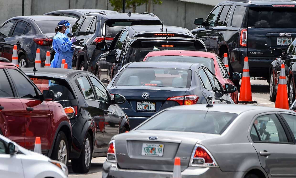 A medical staff member assists people queuing in their cars at a rapid antigen coronavirus testing site at Hard Rock Stadium in Miami Gardens near Miami, on August 5, 2020.