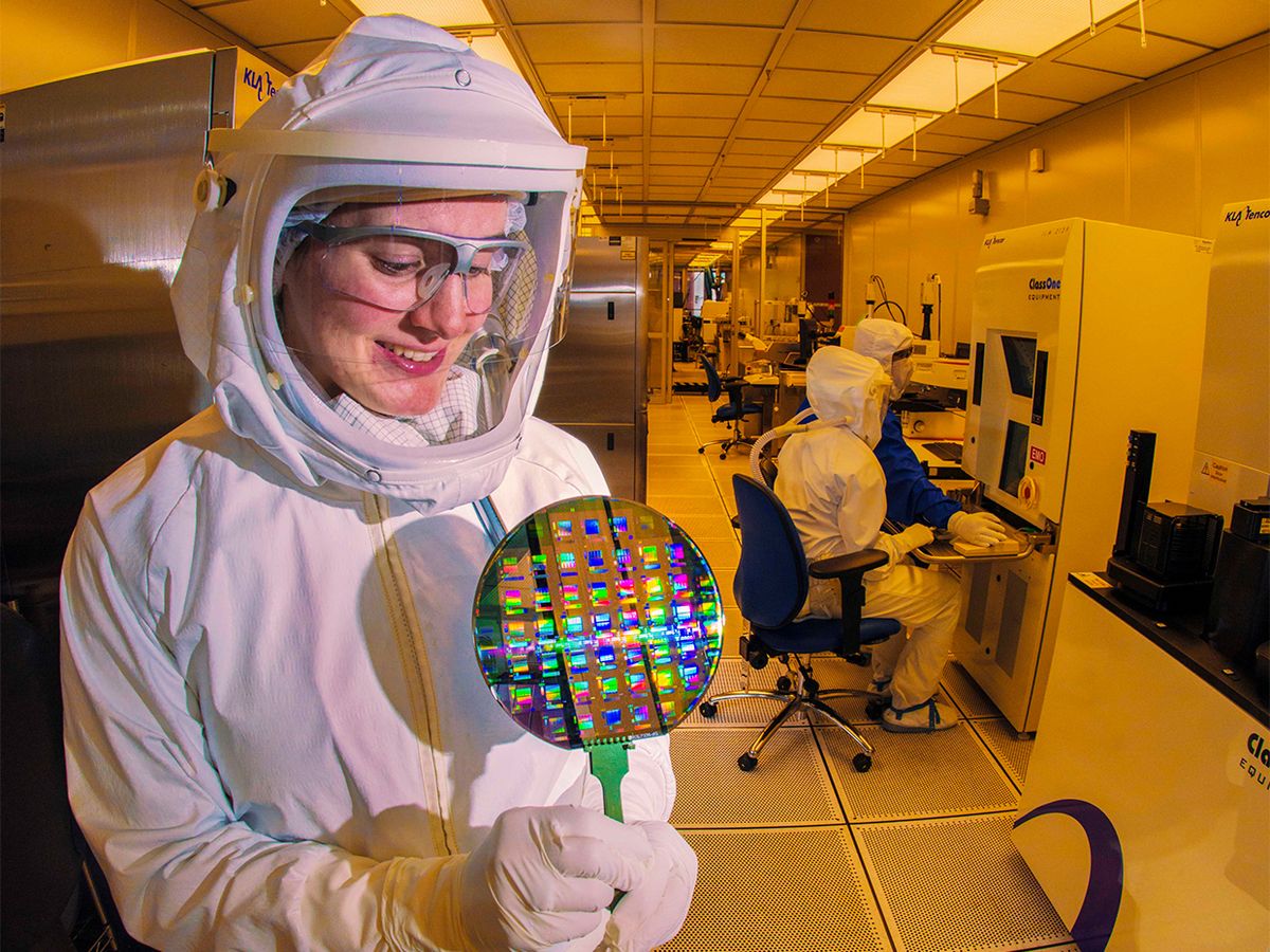 A microelectronics technician at Sandia National Laboratories studies a wafer, a thin slice of semiconductor material used in integrated circuits.