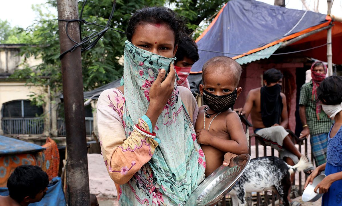 A mother and child queue to receive food during a government-imposed nationwide lockdown as a preventive measure against the COVID-19 coronavirus, at a slum in Kolkata on April 21, 2020. India.