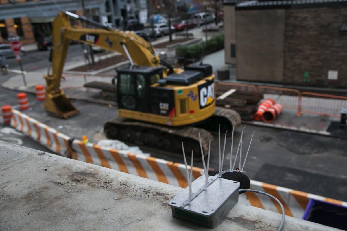 A noise sensor near a street where an excavator is operating at a construction site.