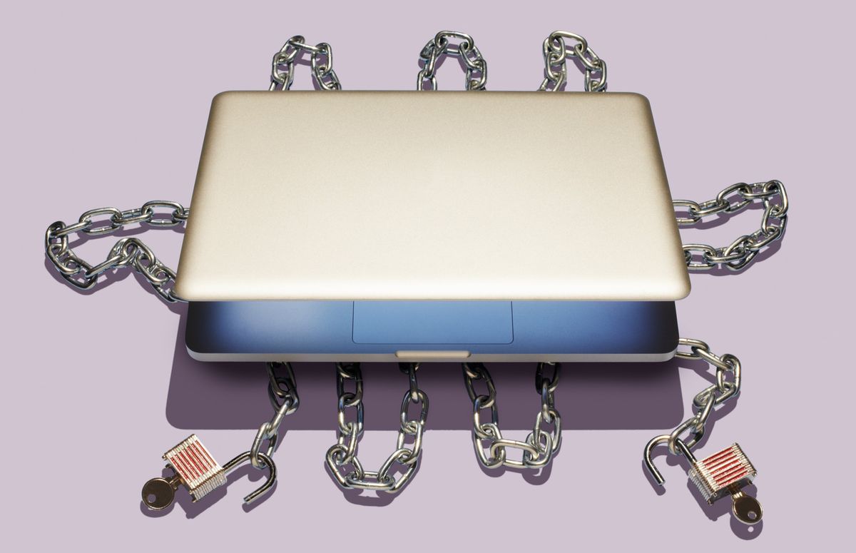 A partially open laptop sits on top of opened chains and padlocks
